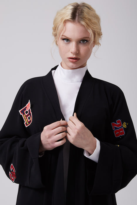 FERADJE black modest abaya with embroidery patches of numbers like a basketball jacket made from crepe close up view