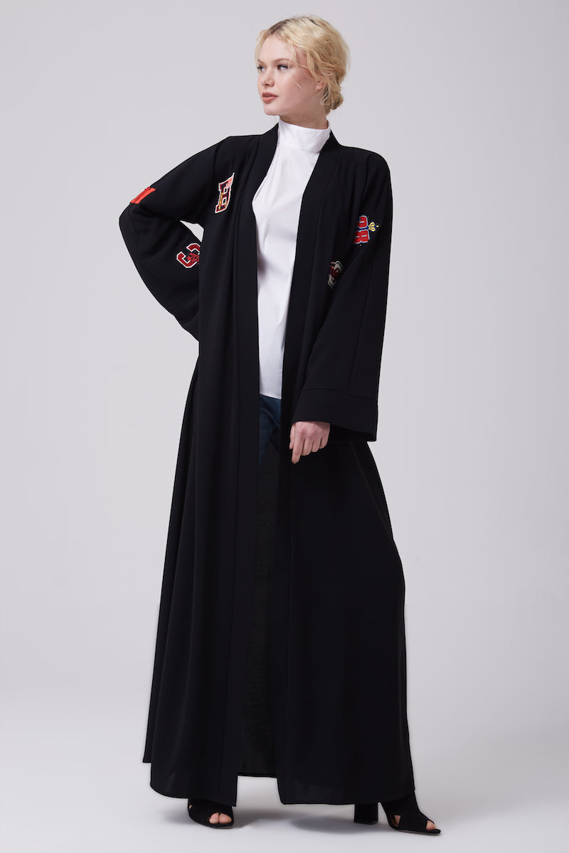 FERADJE black modest abaya with embroidery patches of numbers like a basketball jacket made from crepe full length view